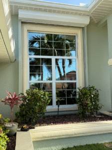 New impact window installed on the front elevation of a Southwest Florida home with palm trees reflected in the glass